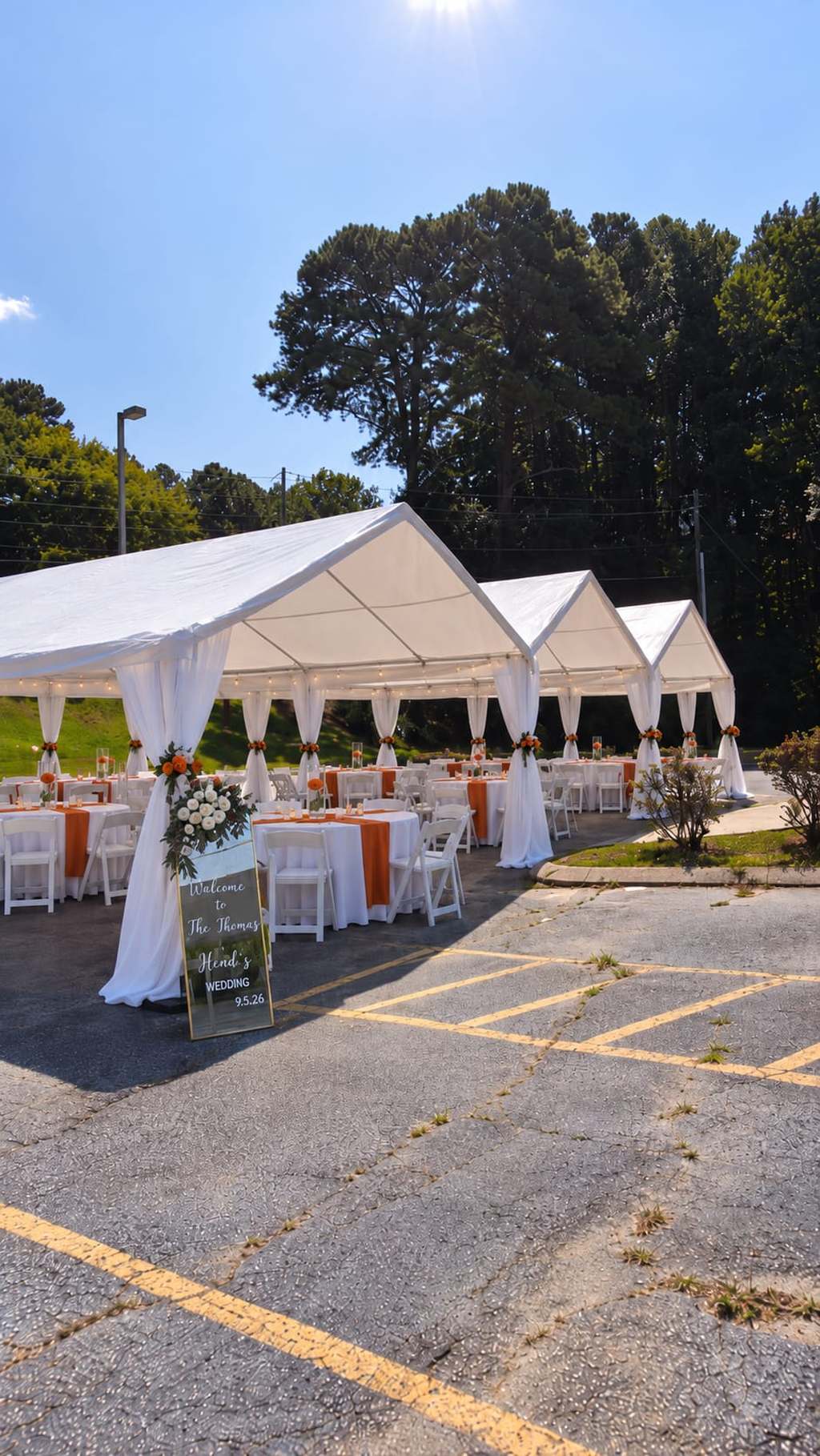 Three connected white tents with draped legs, string lights and terracotta runners set for a wedding reception