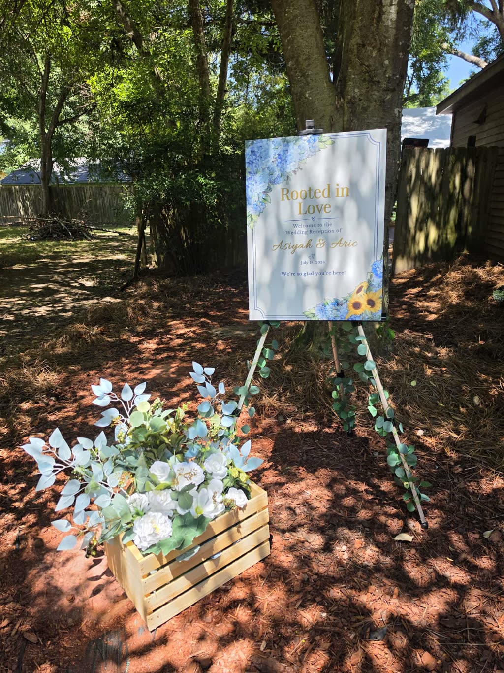 Rooted in Love wedding welcome sign on an easel with eucalyptus garland
