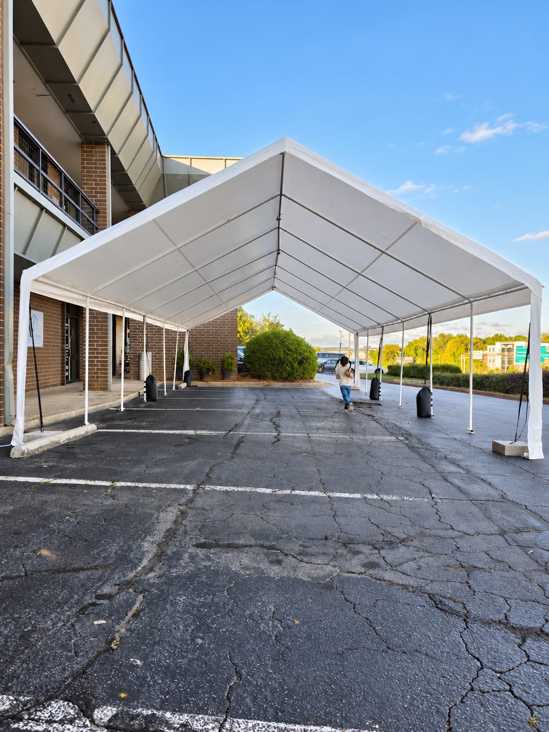 Freshly installed white frame tent on a paved lot before the décor goes in