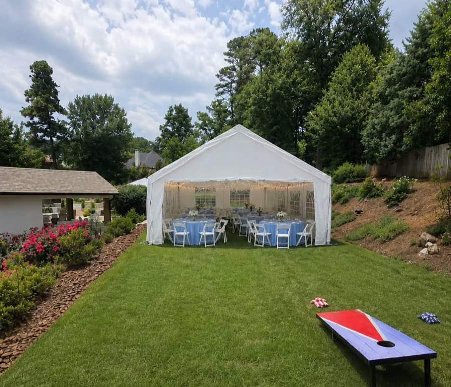 White tent with blue linens and round tables in a backyard