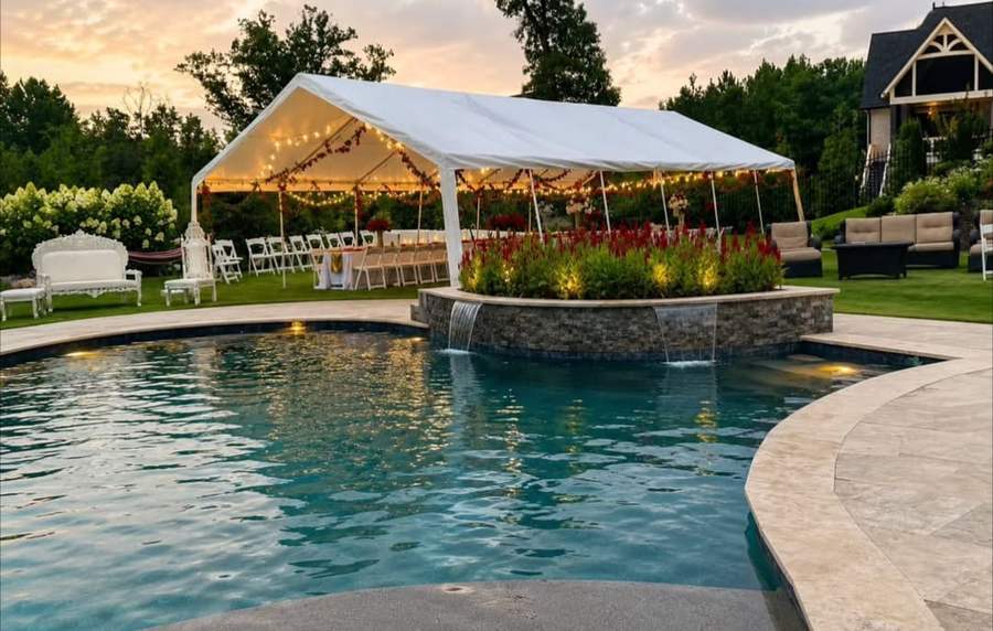 Tent with garlands and lights beside a pool at sunset