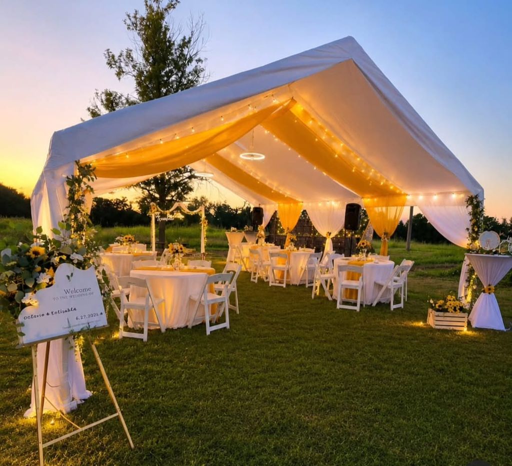White tent at dusk with full table setup and decorated interior