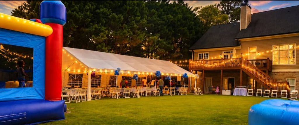 Evening tent lit with string lights beside a blue bounce house