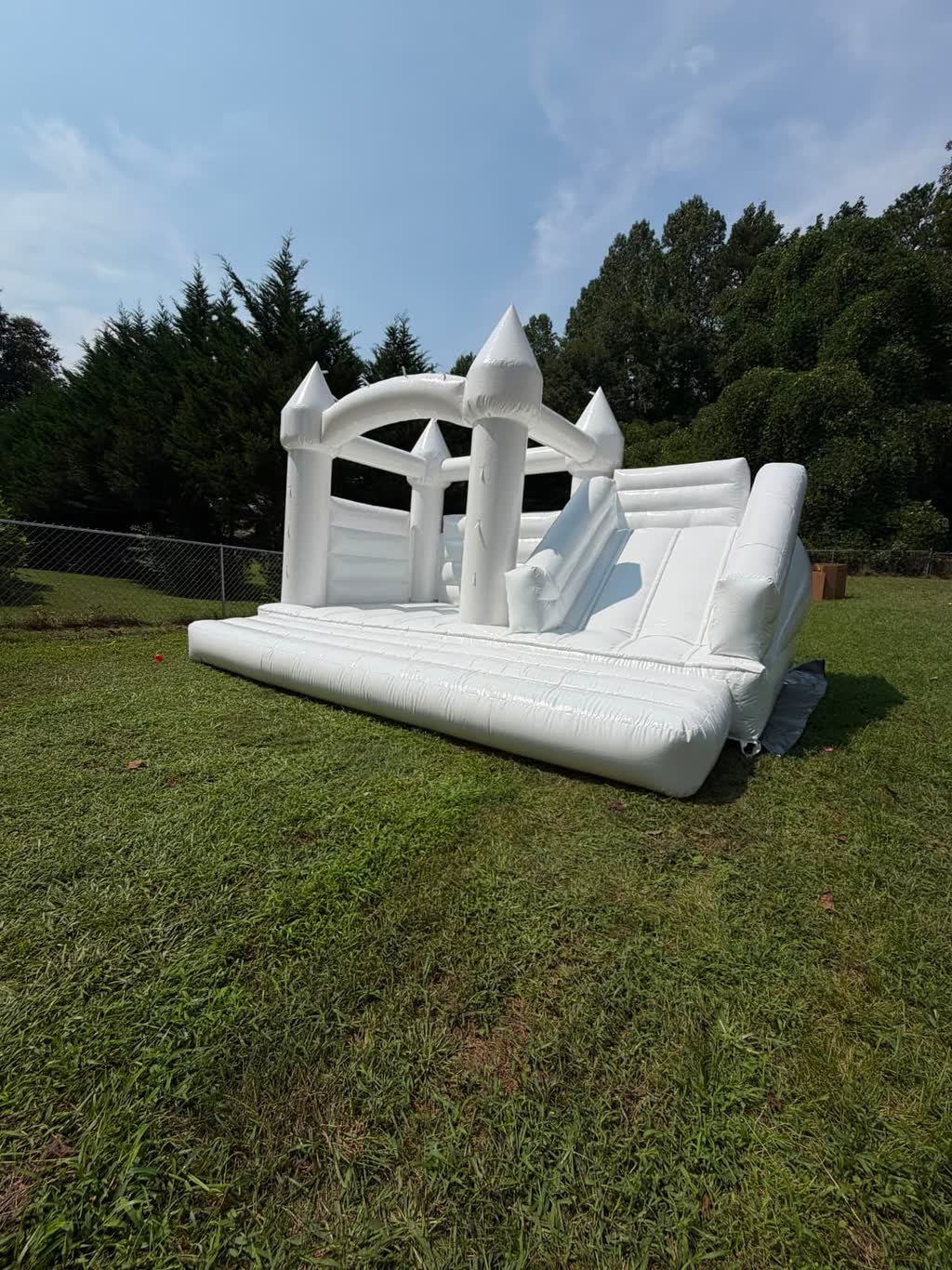 White bounce house with turrets and an attached slide set up on a grass backyard — event rentals in Braselton, GA