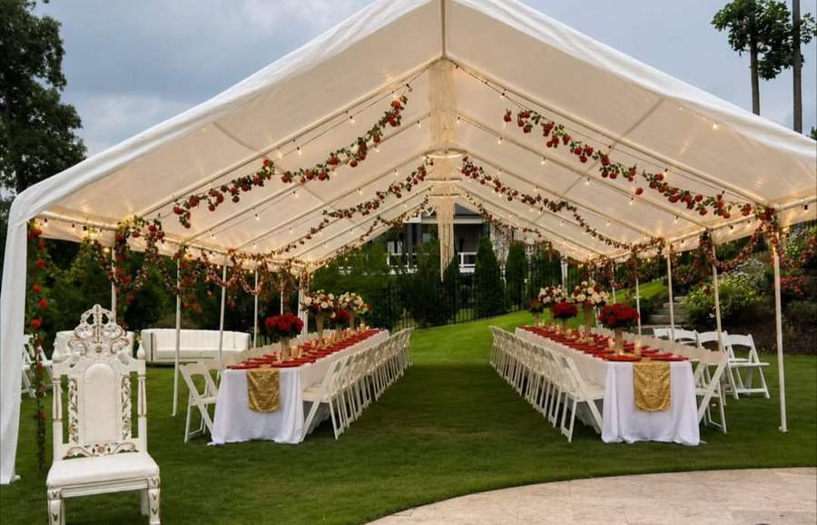 Large tent with red rose garlands and long banquet tables