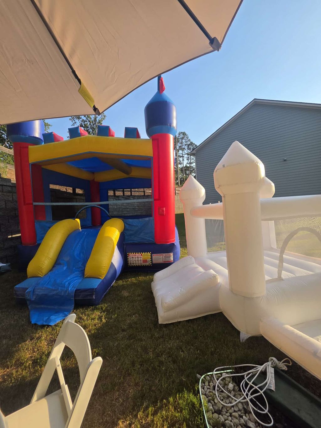 Castle bounce house with slide and a second inflatable in a backyard