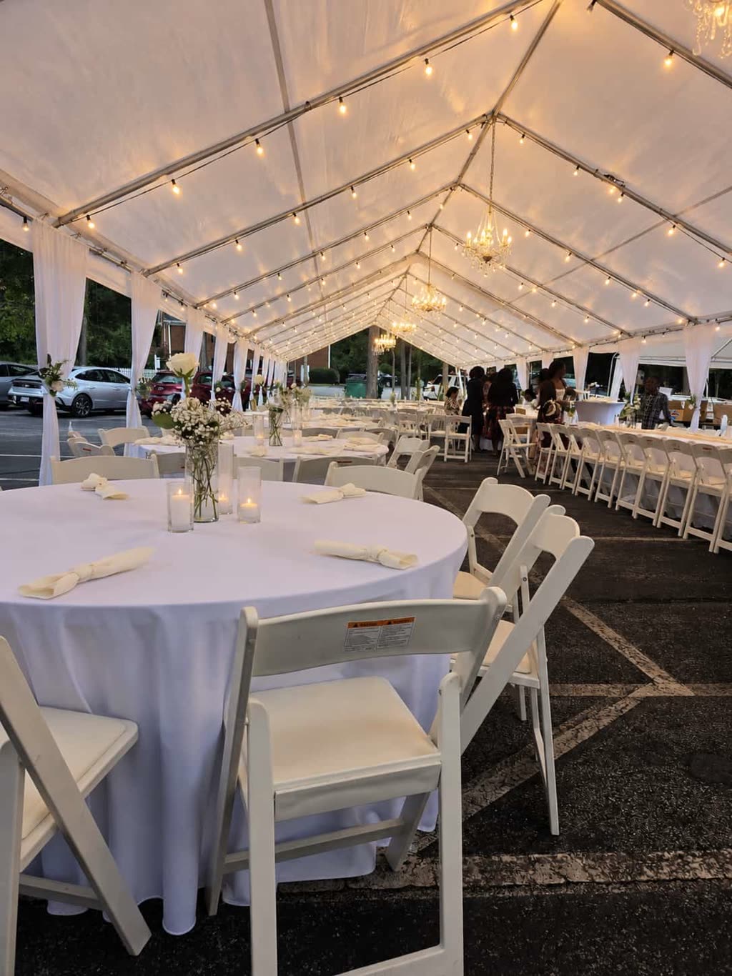 Table centerpiece with baby's breath, pillar candles and an ivory runner on a white banquet table — event setup in Avalon District, Alpharetta, GA