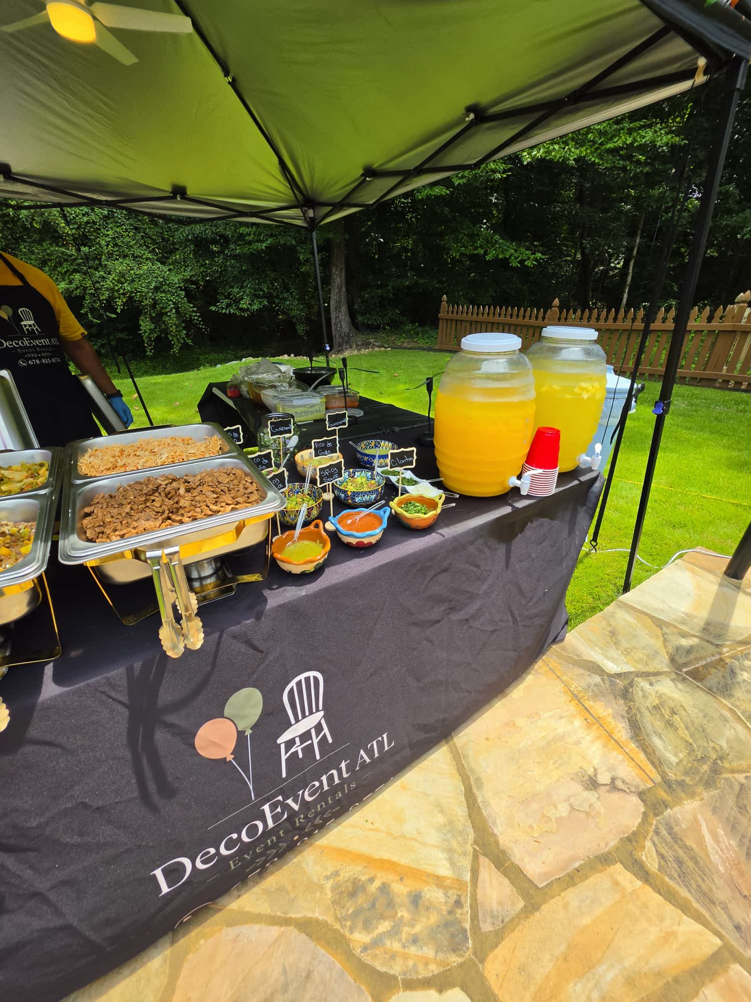 DecoEvent ATL buffet table with chafing dishes, salsas and drink dispensers at a backyard event