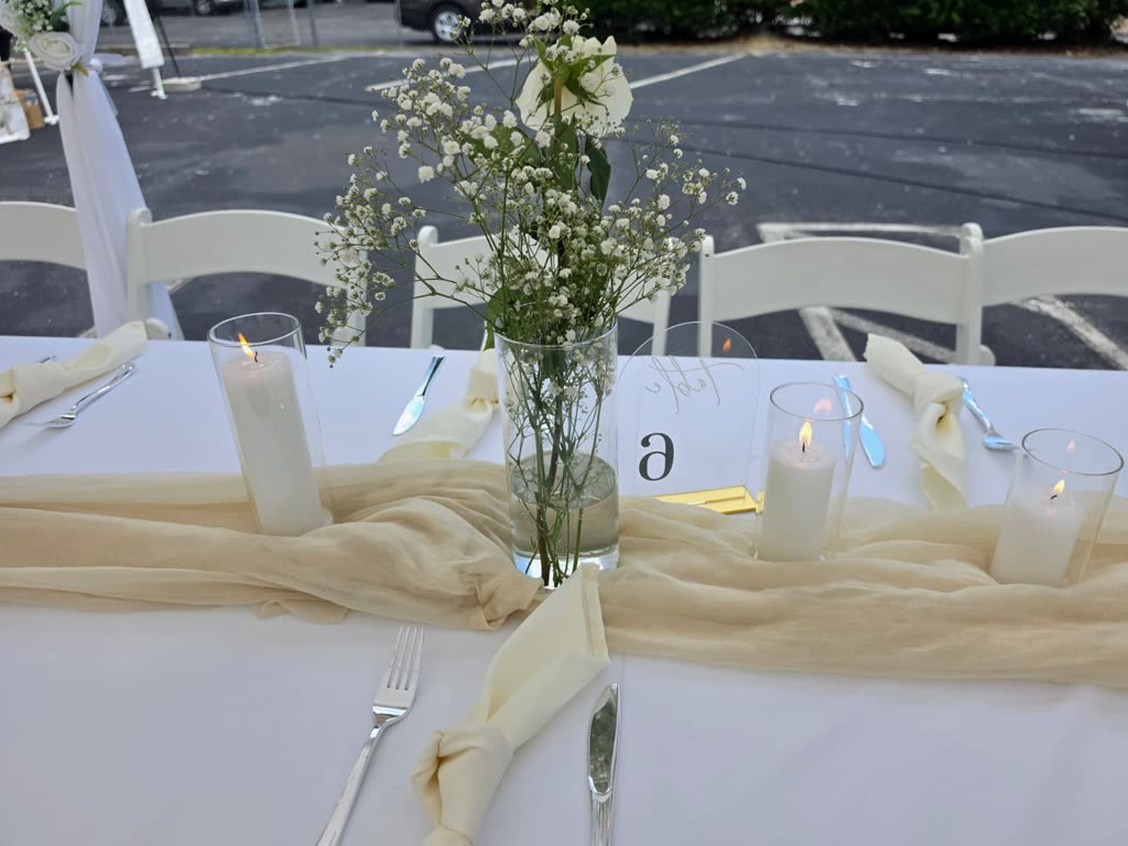 Tent lit at night with round tables in green and blue linens and white folding chairs