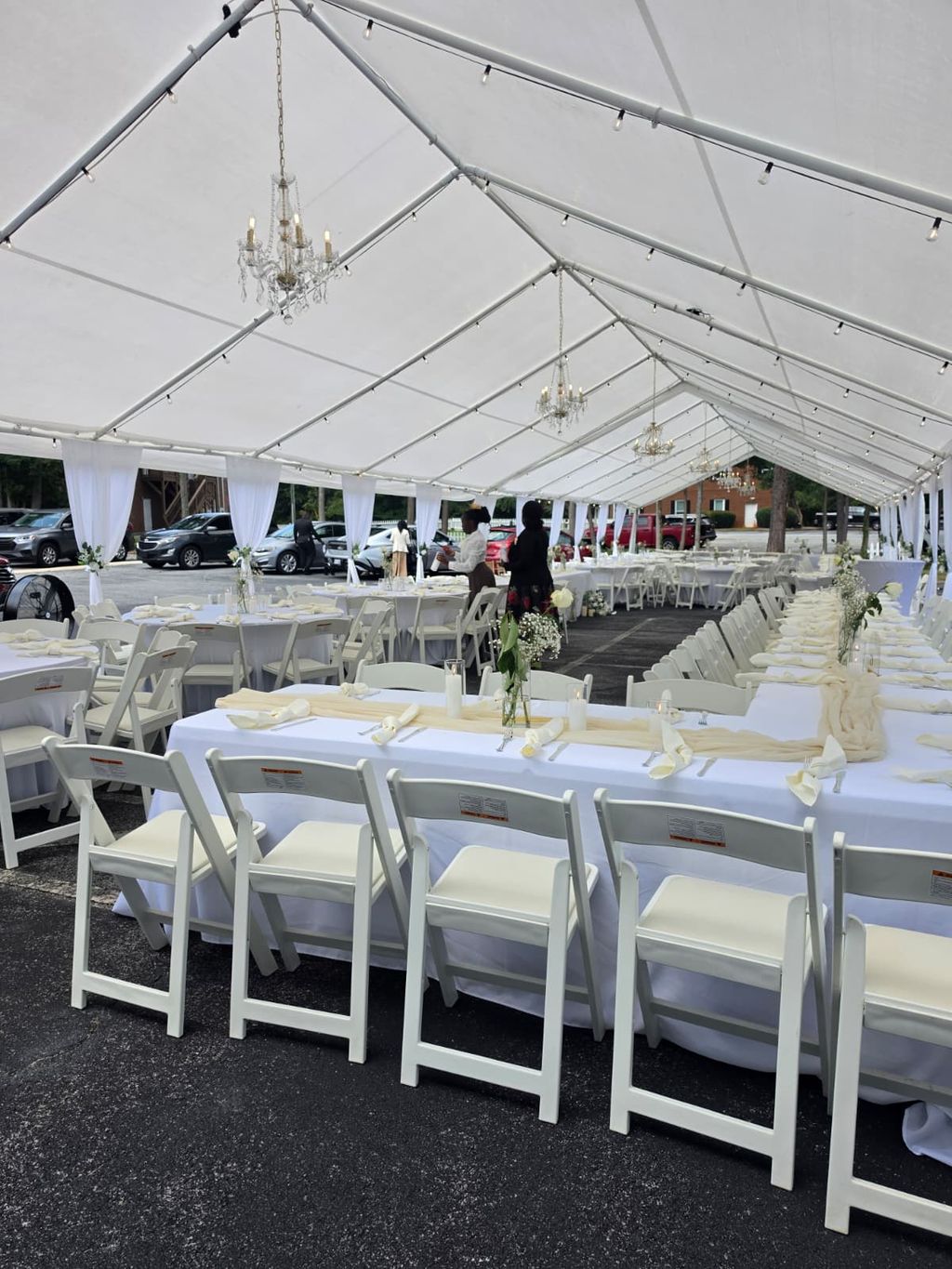 Long banquet tables with ivory chiffon runner, knotted napkins and white rose bud vases